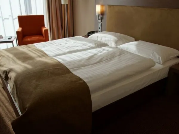 Cameră de hotel amenajată cu lenjerie de pat albă