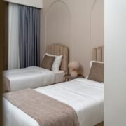 Baie de hotel adaptată, cu duș la nivelul pardoselii, bare de sprijin și scaun rabatabil