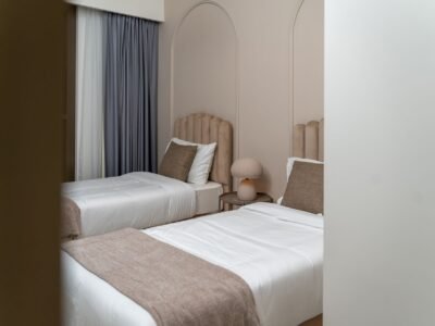 Baie de hotel adaptată, cu duș la nivelul pardoselii, bare de sprijin și scaun rabatabil