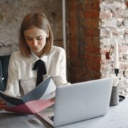 Administratoare de pensiune care citește recenziile oaspeților pe laptop, la biroul de la recepție