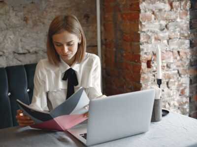 Administratoare de pensiune care citește recenziile oaspeților pe laptop, la biroul de la recepție